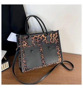 Detail view of leopard print tote bag with black pockets on a wooden surface