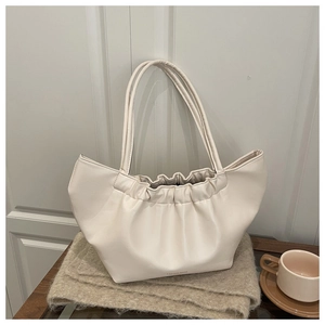 Detail of cream pleated cloud bag with soft leather texture and long shoulder strap