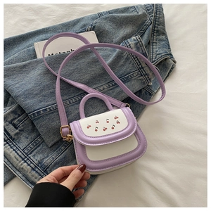 Detail of mini purple and white crossbody bag with cherry print on denim background