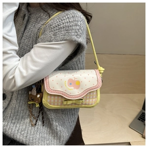 Detail of yellow checkered shoulder bag with pink polka dots and bear pendant