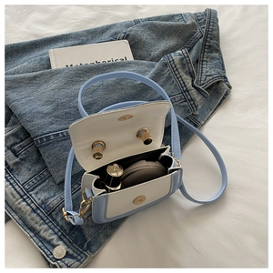 Detail view of mini two-tone crossbody bag showing interior space for small accessories