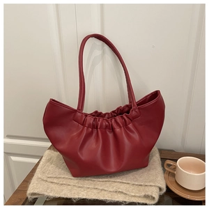 Detail of red pleated cloud tote bag with slim shoulder strap on a cozy scarf