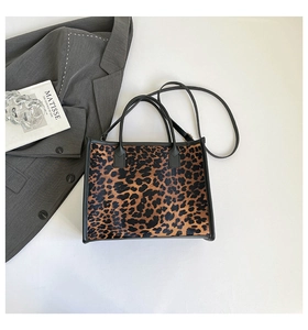 Close-up of leopard print tote bag with dual straps on white desk with aesthetic props
