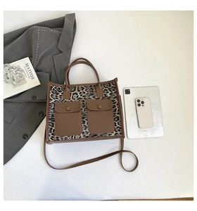 Detailed view of leopard print tote bag with brown leather handles and front pockets