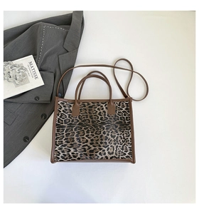 Overhead view of leopard print tote bag with brown straps next to fashion props