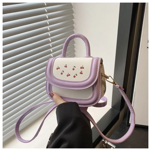 Detailed view of mini purple cherry bag with cream panel and golden hardware accents