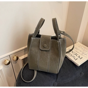 Detailed view of dark olive bucket bag featuring white contrast stitching and soft texture