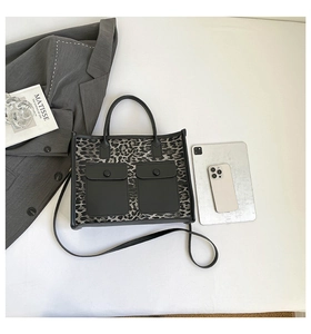 Detail of leopard print tote bag featuring black cargo pockets and detachable strap