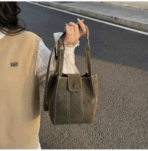 Close-up of olive green vintage bucket bag with white contrast stitching and leather texture