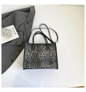 Detail of leopard print tote bag with black handles and detachable shoulder strap