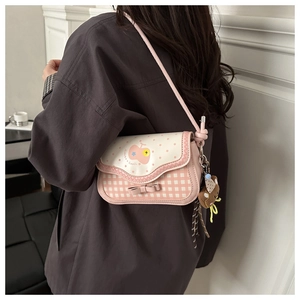 Detailed view of pink plaid crossbody bag with bow decoration and cute bear charm