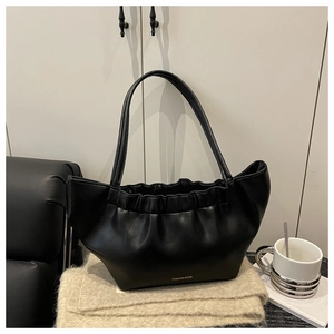 Close-up of black pleated cloud bag with soft leather texture and printed fashion text