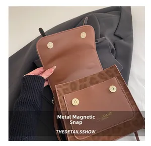 Dettaglio della chiusura magnetica in metallo della borsa a tracolla in pelle marrone