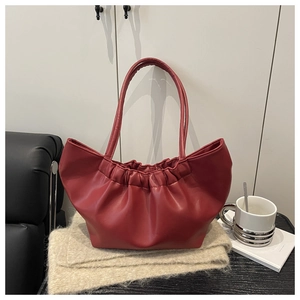 Macro detail of dark red ruched tote bag with soft faux leather texture and gather design
