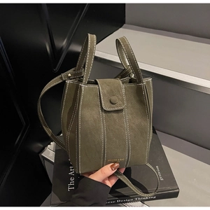 Detail view of dark green retro bucket bag featuring contrast white stitching and gold logo