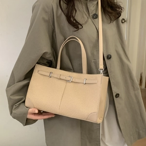 Minimalist beige crossbody bag in textured fabric with leather trim shown on a model