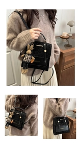 Detail view of black handbag with leopard print flap and plush bunny pendant accessory