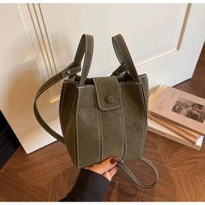 Detail of olive green bucket bag featuring white contrast stitching and soft matte texture