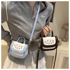 Detail of mini cherry print PU handbags in blue and brown with gold hardware