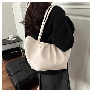 Detail of cream pleated leather hobo bag with Fashion Bags print and long slim straps