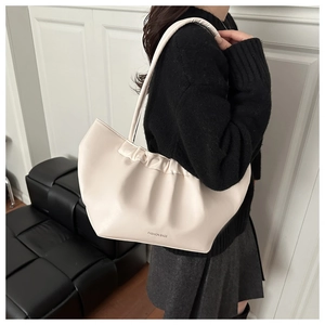 Detail of a creamy white pleated shoulder bag with a soft texture and fashion bags lettering