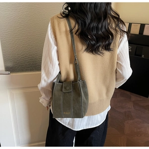 Detail of dark green vintage crossbody bag with white stitching shown on a model