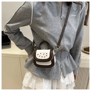 Close-up of mini girls' crossbody bag with cherry embroidery and gold hardware