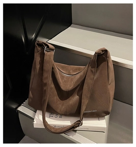 Dettaglio borsa hobo in camoscio marrone capiente con logo e tracolla larga