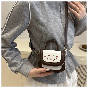 Detail of mini crossbody bag with cherry print and contrast brown leather straps