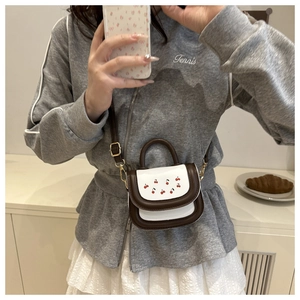 Selfie allo specchio di una mini borsa bianca a tracolla con stampa ciliegia e manico