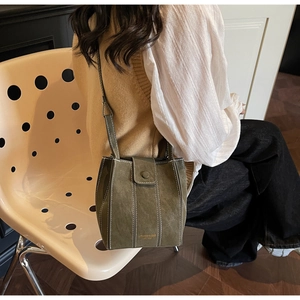 Detail of dark green vintage bucket bag with white contrast stitching and long strap