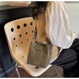 Olive green crossbody bucket bag with white contrast stitching and minimalist matte leather