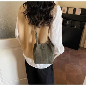 Detail of vintage green bucket bag with white stitching shown on model's shoulder