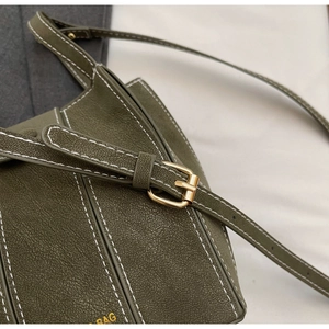 Detail of olive green pebbled leather bag featuring white stitching and gold buckle