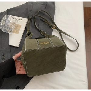 Detail of dark green suede bucket bag with white stitching and gold branding