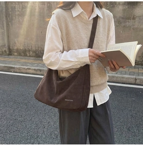 Dettaglio della borsa hobo in pelle scamosciata marrone scuro con logo bianco stampato