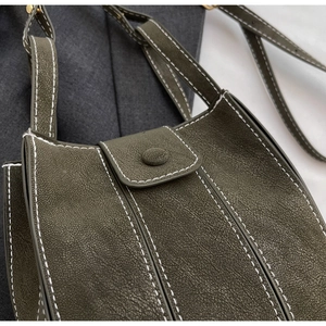 Close-up of olive green crossbody bag with contrast stitching and matte leather texture