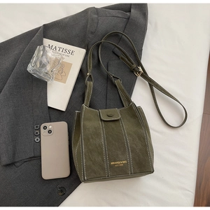 Detail of dark green matte leather bucket bag with white stitching and gold hardware