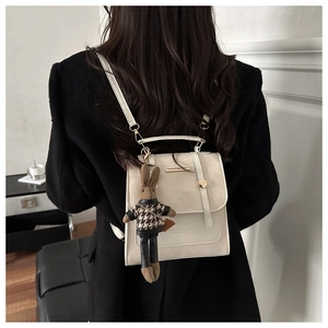 Detail of white PU leather backpack with gold metal bar and cute rabbit charm