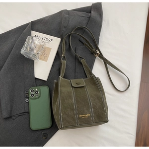 Detail of dark green matte shoulder bag with vertical stitching and brand logo texture