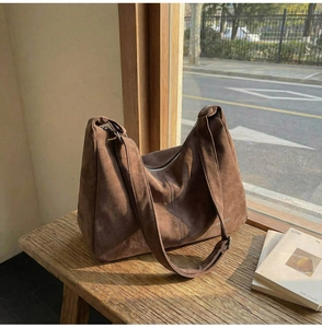 Dettaglio della borsa tote in pelle scamosciata marrone scuro su una panca di legno