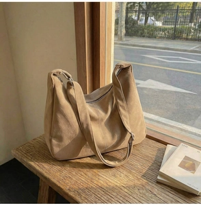 Dettaglio borsa hobo in pelle scamosciata marrone con tracolla larga su panca di legno