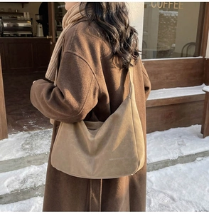 Dettaglio della borsa hobo in pelle scamosciata con incisione AINUSSTUDIO sulla neve