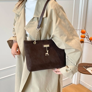 Brown suede tote bag with leather strap, gold chain and deer pendant in fall setting