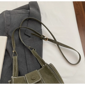 Detail of olive green pebbled leather bag with white contrast stitching and gold hardware