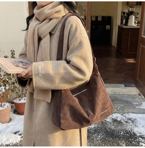 Dettaglio borsa hobo in pelle scamosciata marrone scuro con cerniera argentata e logo