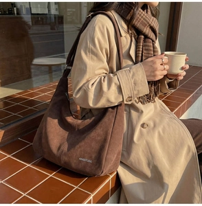 Dettaglio di una grande borsa hobo marrone scuro in morbida pelle opaca con logo bianco