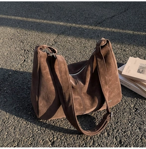 Dettaglio della texture della borsa tote in pelle scamosciata marrone con logo al sole