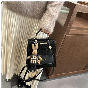 Detail of leopard print flap backpack with gold hardware and knit bunny charm