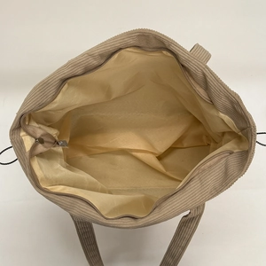 Beige corduroy tote bag with large interior capacity and zipper closure on white background